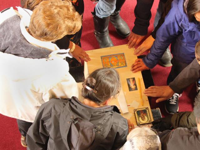 Worhsipers gather round and touch plain wooden casket.