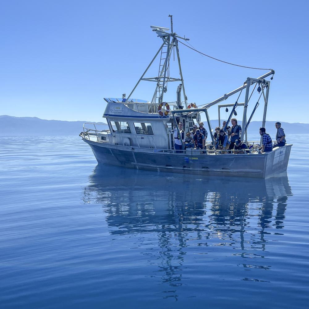 Group of scientists and politicians aboard the UC Davis research vessel under blue skies and on blue water at Lake Tahoe