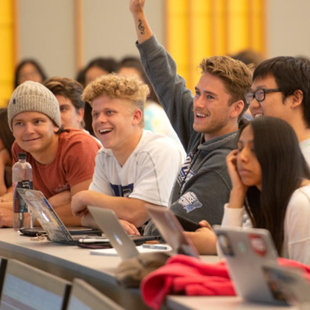 a student raising their hand in a lecture hall
