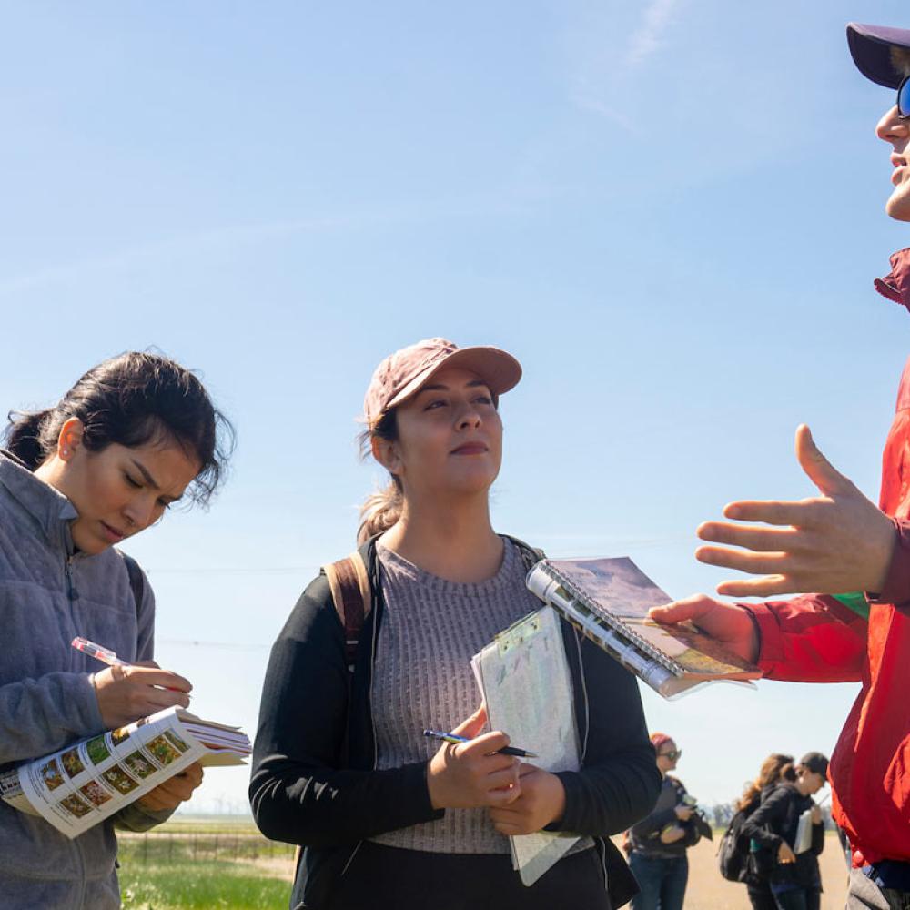 A student teacher lectures his class in the field