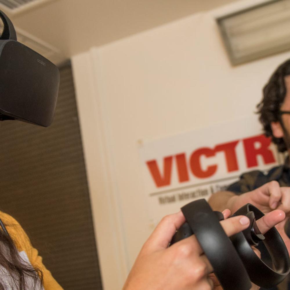 a student wearing VR goggles while a professor is guiding