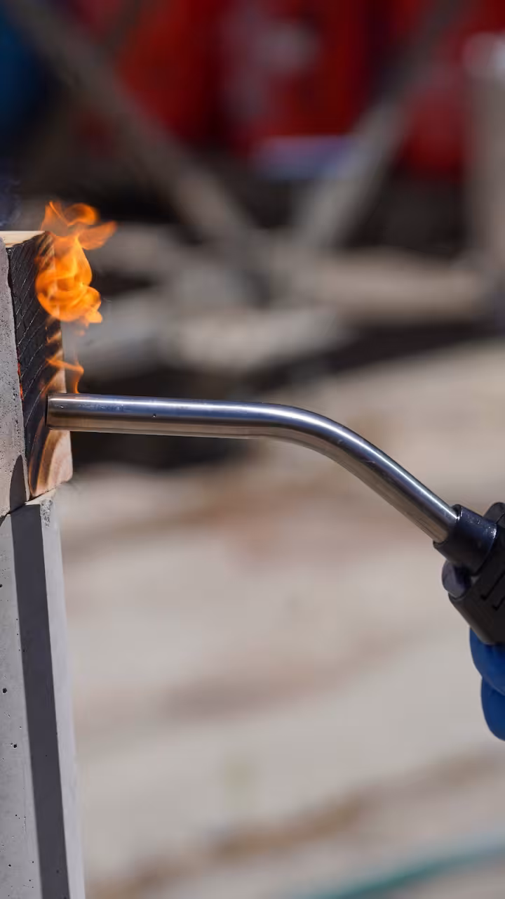 A close-up of a wood block and earth block and a blowtorch