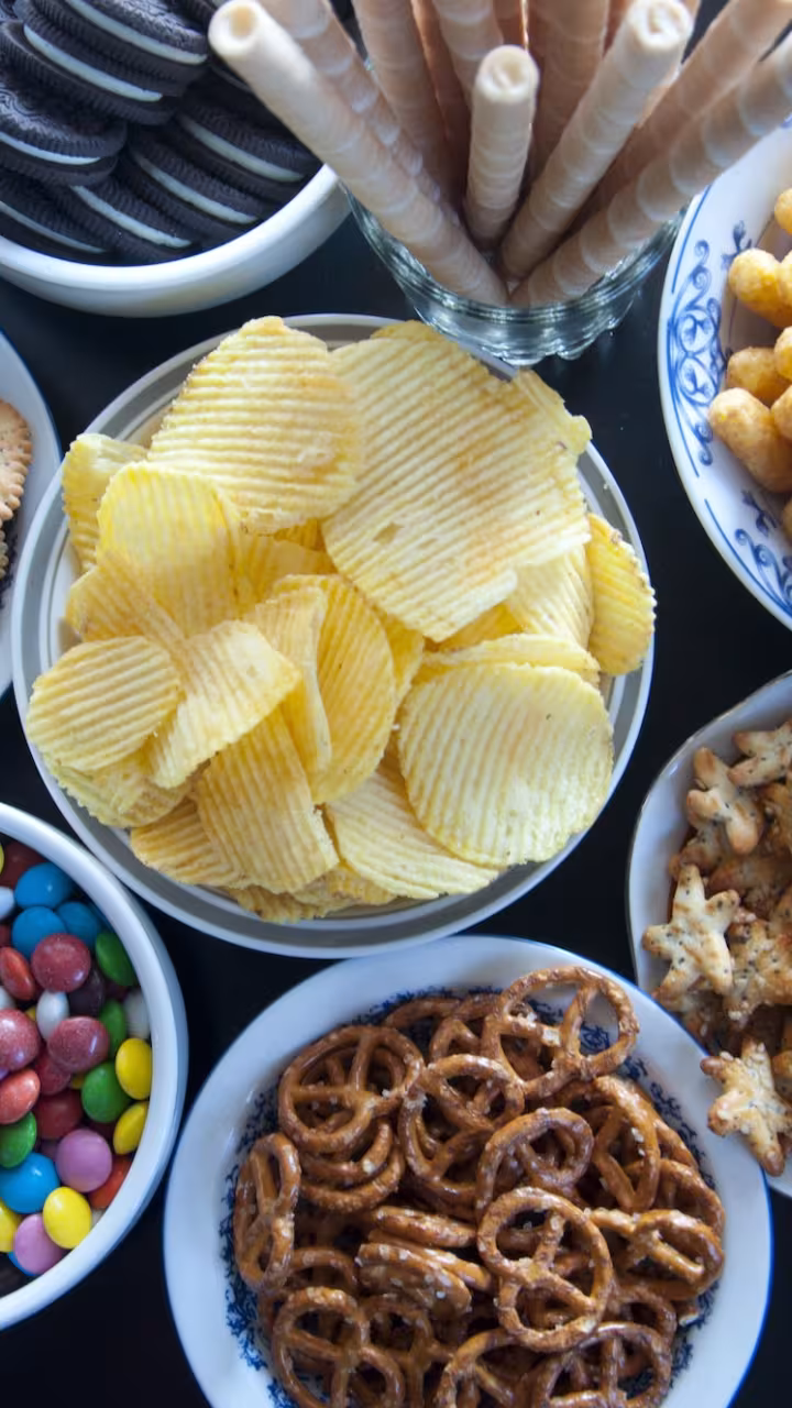In this episode of Unfold, we uncover the science and debate behind processed and ultra-processed foods. Shown here are eight bowls with various processed and ultra-processed foods, including chips, pretzels and candies.(Getty)