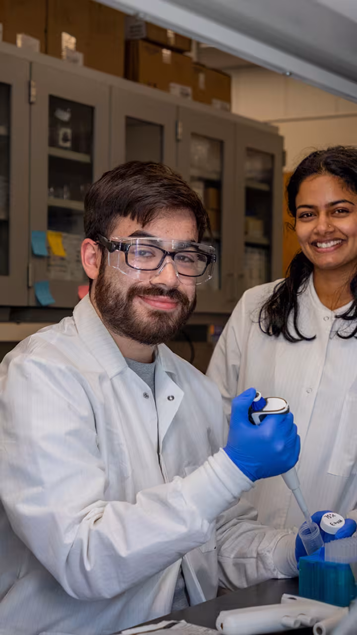 Three researchers in lab coats smile for the camera