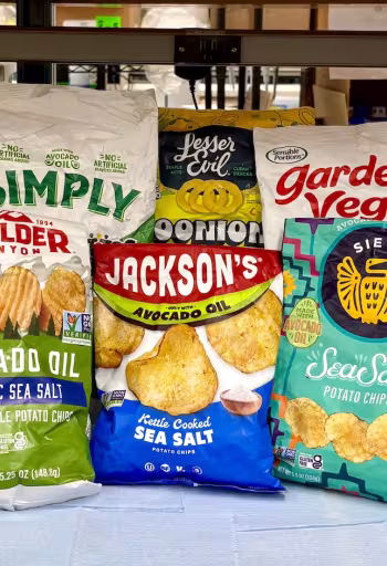 Assorted colorful chip and snack bags that claim they are made with avocado oil are lined on a table inside a lab. These chips were among the 54 avocado-labeled products tested in the Wang lab at UC Davis. (Selina Wang / UC Davis)