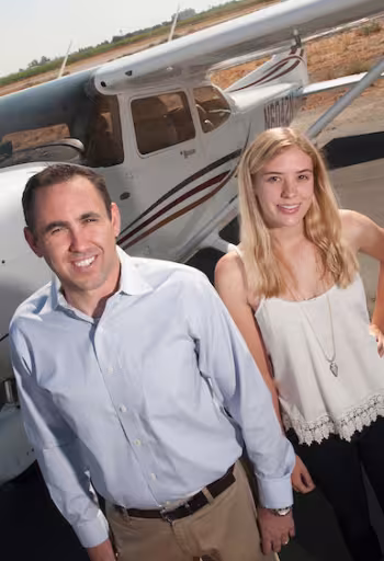 An instructor and student pose for a shot in front of an airplane at UC Davis airport