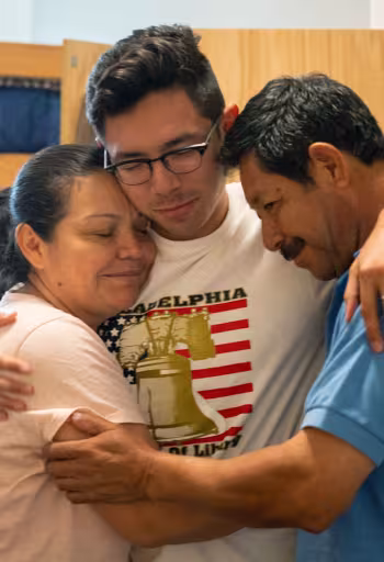 parents hugging their child in a dorm room