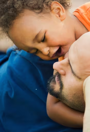 a toddler plays with his dad on the grass in Davis's central park