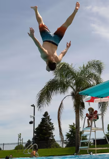 A student doing an acrobatic jump of of the diving board at the UC Davis Recreation Pool