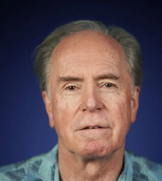 Portrait photograph of person with gray hair, blue patterned shirt, neutral expression