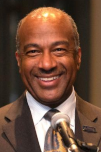 Man in a suit smiling in front of a microphone