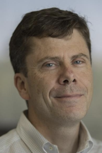 Headshot of a middle-aged man with slight smile, collared shirt, neutral background