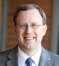 Man in gray suit in front of wooden background