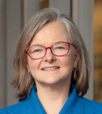 Woman with glasses in blue in front of neutral background