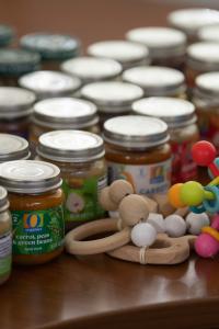 Glass jars of baby food arranged on a table, alongside colorful wooden baby toys.