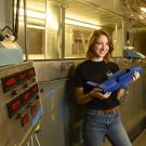 student holding a model rocket in front of lab equipment