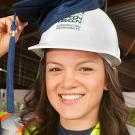 Woman putting a graduation cap on top of a hard hat