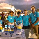 Francesca D'Cruz with friends at an information booth outdoors. 