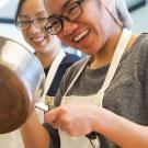 Woman in a hairnet holding a sauce pan