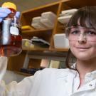 Lynne Hagelthorn holds up a vial in a lab. 