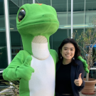 A sociology major gives a thumbs up as she poses with a person in a Geico Gecko suit. 