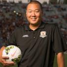 Political science graduate Brent Sasaki holding a soccer ball