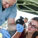 A health professional showing a student how to make a suture