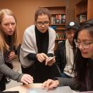 Economics lecturer Janine Wilson discusses a theory with Andrea Romero, Daniel Moon and Julia Tien, all economics majors