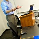 Male teacher standing at short podium and gesturing