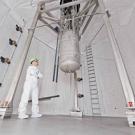 Man in white suit in a huge tank looking at a hanging dark matter detector