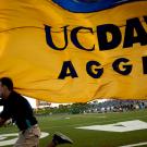 Photo: Man runs into Aggie Stadium carrying giant UC Davs Aggies flag.