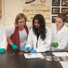 A professor and students look at experiment results at a lab bench.