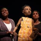 Student actors flank puppet.