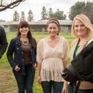 Photo: a male and three femal students standing in a field with two cows