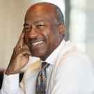 Chancellor Gary S. May smiles, sitting at desk.