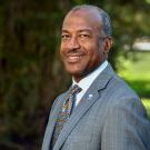 Chancellor Gary S. May standing in front of a tree, smiling.