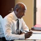 Chancellor Gary S. May sitting at a desk, writing.