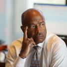 Chancellor Gary S. May, at desk, hand to cheek, serious