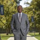 Chancellor Gary S. May, standing, smiling, portrait on Quad.