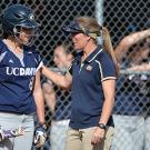 A softball coach, right, talking to a batter in a helmet