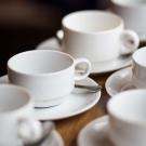 Five white coffee cups and saucers