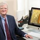 Scientist in front of computer holding vaccine patch device