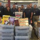 Mail Services crew, lined up behind mail bins full of donated food