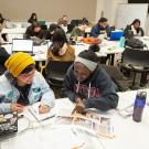 Students works in groups, at tables, in design class.