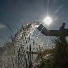 Water flows from a large pipe as a man monitors the well flow rate