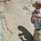 Eldridge Moores gestures in front of a rock face.