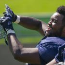 Two football players, one holding helmet and laughing, the other with helmet on