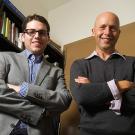 Two men posing in a book-lined office