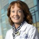 Smiling woman in a doctor's white coat and a leopard skin scarf