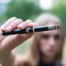 A girl holds an e-cigarette